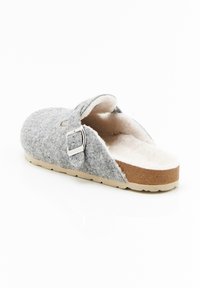 Grijze slip-on klompen met verstelbare zilveren gesp, gevoerde witte fleece binnenkant en tan kurken zool, in een hoek geplaatst om de binnen- en zijkantdetails te tonen.