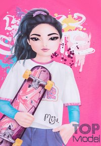 T-shirt rosa con un personaggio dai lunghi capelli scuri, che tiene un skateboard con grafiche rosa e accenti blu sulle maniche. Il testo nel design include "Top Model."