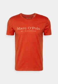 Rød bomulds t-shirt med rund hals, korte ærmer, der har hvid tekst "Marc O'Polo EST. IN STOCKHOLM" trykt på forsiden.