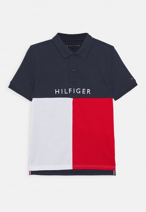 Tmavě modrá polokošile s bílými a červenými barevnými bloky, krátkými rukávy, zapínáním na dva knoflíky a nápisem „HILFIGER“ přes hrudník.