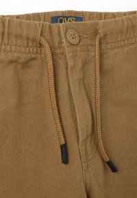 Bruine katoenen broek met een zachte textuur, elastische tailleband, knoopsluiting en trekkoordaccenten. OVS-label zichtbaar.