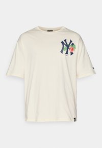Cream cotton t-shirt with short sleeves. Features a dark blue NY logo and a peach graphic on the left chest. Tag on the lower left side.