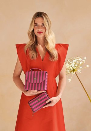 Pink and dark gray striped handbag with a handle and zipper wallet held by a person wearing a red dress with wide sleeves.