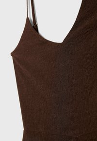 Débardeur marron texturé avec fines bretelles et encolure en V. Le tissu présente un motif côtes pour plus de détails.