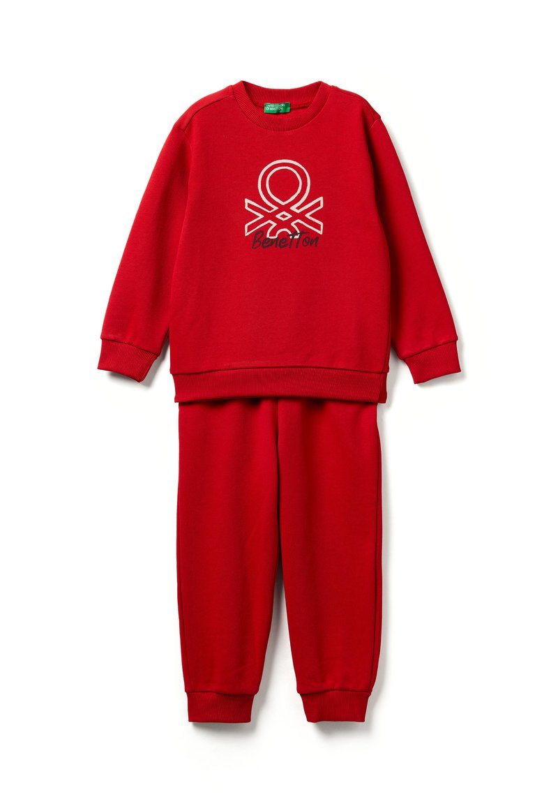 Červená souprava mikiny a kalhot s žebrovanými manžetami, na přední straně mikiny uprostřed je bílo-černé logo Benetton.