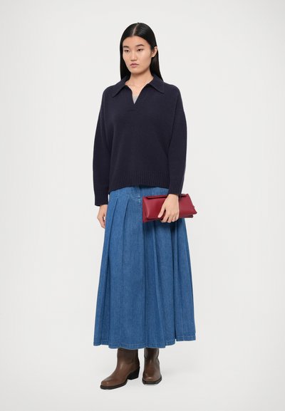 Dark navy knitted sweater with a V-neck, paired with a long denim skirt. Red clutch and brown ankle boots complete the outfit.