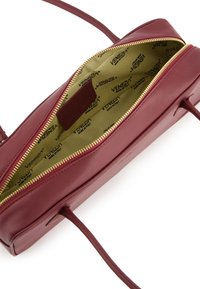 Maroon leather handbag with a golden zipper, featuring a smooth texture. Interior lined with branded beige fabric. Includes adjustable strap.