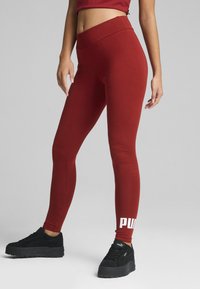 Punttihuiset punaiset legginsit, joissa on sileä pinta ja tiukka muotoilu, ja jalassa on valkoinen "PUMA" -logo.