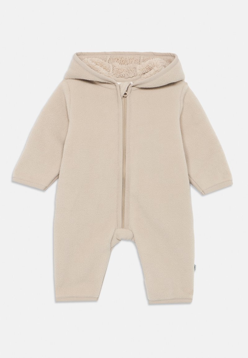 Bežový fleece overal so zipsom vpredu a kapucňou, vybavený mäkkou podšívkou, dlhými rukávmi a zakrývajúcimi nohami.