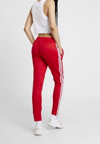 Röda träningsbyxor med vita sidostrapper, elastisk midja och framfickor, kombinerat med en vit kortärmad ribbad topp.