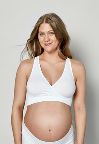 Weißer Still-Bralette aus glattem Stoff mit V-Ausschnitt und Wickeldesign, verstellbaren Trägern und nahtlosen Kanten.