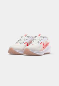 Zapatillas deportivas blancas y rosas con una parte superior de malla, cordones texturizados y una suela de goma que presenta un acento rosa en el talón y un logo rojo.