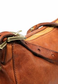 Borsa in pelle marrone chiaro con zipper in bronzo, cuciture rinforzate e dettaglio a fibbia su una tracolla, che mostra una texture liscia e una finitura morbida.