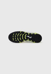 Suola di scarpa sportiva con fondo in gomma nera testurizzata, caratterizzata da elementi di trazione verdi e un dettaglio del logo bianco. Design liscio e curvo.