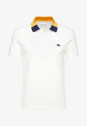 Wit polo met korte mouwen, gele en marineblauwe kraag en klein marineblauw krokodillenlogo op de linkerborst.