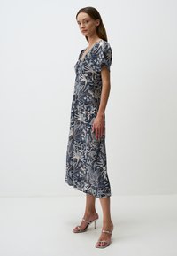 Bloemenprint jurk in marineblauw en crème, met korte puffmouwen, een V-hals en een vloeiende silhoeet die tot halverwege de kuit reikt.