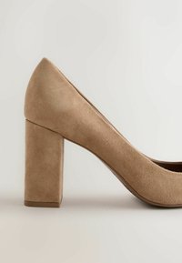 Escarpin beige en daim pour femme avec bout arrondi et talon bloc moyen sur fond neutre.