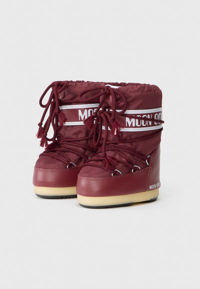 Cizme de zăpadă Burgundy Moon Boot cu talpă groasă bej, superior din nylon căptușit și sireturi încrucișate legate în față și la partea superioară.