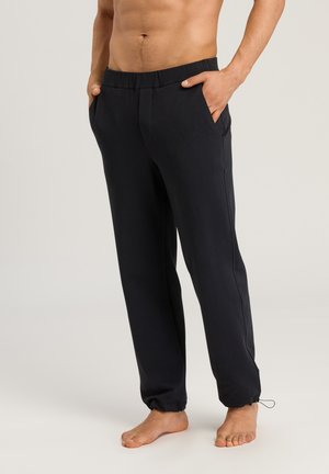 Black relaxed-fit joggers made of soft fabric, featuring an elastic waistband, side pockets, and elastic cuffs at the ankles.