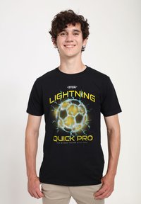 Černé bavlněné tričko s živou grafikou fotbalového míče obklopeného blesky, s nápisy "LIGHTNING" a "QUICK PRO" vytištěnými žlutou barvou.