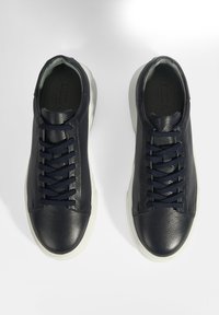 Navyblaue Ledersneaker mit strukturierten Obermaterialien, flachen navyblauen Schnürsenkeln und weißen Gummisohlen. Mit einer abgerundeten Zehenpartie und minimalistischem Design.