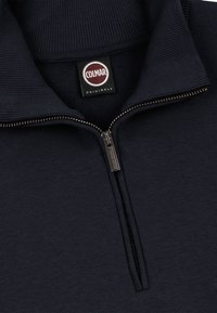 Marineblauer Pullover mit Viertel-Reißverschluss aus strukturiertem Stoff. Verfügt über einen gerippten Kragen und ein Markenetikett. Inklusive eines metallischen Reißverschlusses mit Zipper.