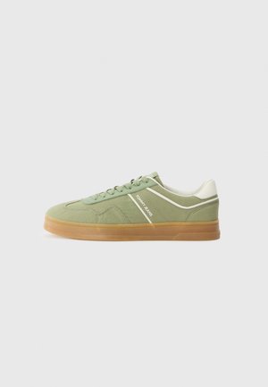 Green suede sneaker with a white leather accent stripe, lace closure, and gum rubber sole. Flat design with rounded toe for casual wear.