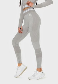 Graue hochtaillierte Leggings mit strukturierten Mustern und gerippten Akzenten, kombiniert mit weißen Sneakers. Sie verfügt über ein figurbetontes Design für Sportbekleidung.