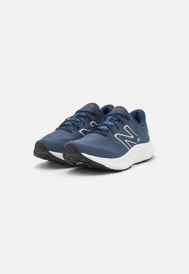 Blaue Sportschuhe mit einem strukturierten Mesh-Obermaterial, weißer Sohle, grauen Akzenten und einem auffälligen "N"-Logo an der Seite. Leichtes Design.