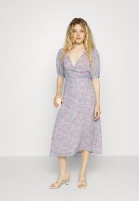 Vestido envolvente floral com um decote em V profundo, mangas bufantes e uma bainha de comprimento médio. Apresenta uma palete de cores pastel em rosa e azul claro.