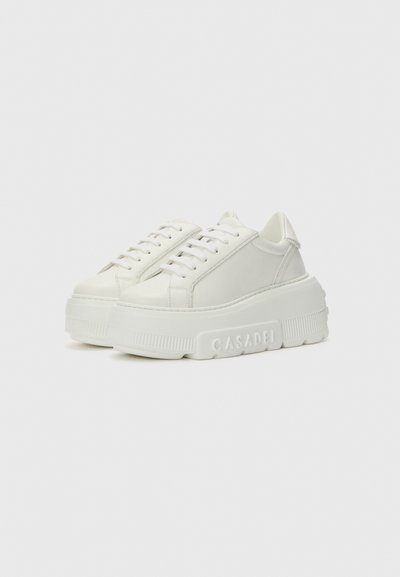 White platform sneakers with a smooth leather upper, lace closure, and textured rubber sole featuring embossed brand logo on the side.
