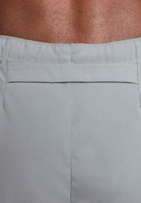 Ljusgrå shorts gjorda av en slät tyg. Har en bakficka med lock och snygg sömnad längs sömmarna.