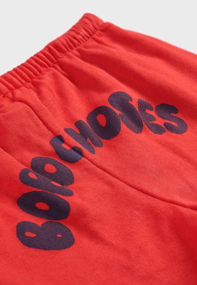 Rote Baumwollshorts mit elastischem Bund, die mit auffälligem marineblauen Text bedruckt sind, der "Bobo Choses" liest. Weiche Textur mit einem schlichten Design.
