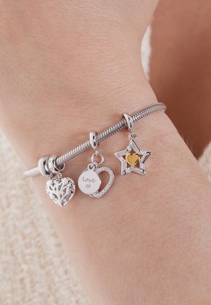 Bracelet en argent avec trois breloques : un cœur feuillu, une breloque circulaire portant l'inscription "amour" et une étoile avec un accent en cœur doré.