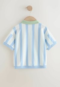 Kortærmet polo med lodrette blå og hvide striber, med krave i lys grøn og blå ribkant, hængende på en træknage.