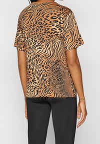 Kortærmet t-shirt med dyreprint, der kombinerer leopard-, zebra- og slange-mønstre i varme nuancer af orange og sort.