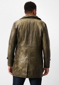 Olive green leather coat with a classic collar, back seam detailing, and a relaxed fit, featuring smooth, textured leather.