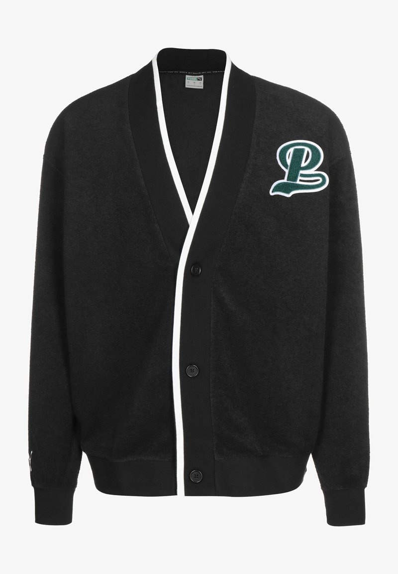 Svart cardigan laget av myk stoff, med V-hals, hvit kant, knappelukking og grønn brodert "P"-logo på venstre bryst.