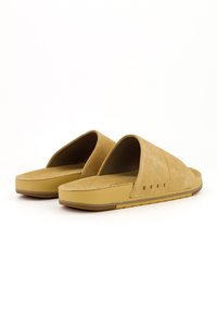 Sandales en daim à glissière de couleur marron clair avec une semelle plate. Elles disposent d'une large bride supérieure et d'un semelle intérieure texturée. Le nom de la marque "REEF" est inscrit sur le côté.