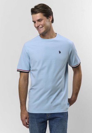 Világoskék rövid ujjú póló puha anyagból, kerek nyakkivágással, fekete és piros csíkozással a ujjakon, valamint egy kis logóval.