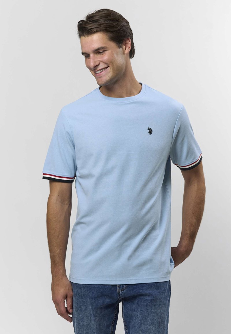 Ljusblå kortärmad t-shirt i mjukt tyg med rund halsringning, med svarta och röda randiga detaljer på ärmarna och en liten logga.