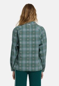 Groene geruite shirt met lange mouwen, voorzien van witte en donkergroene patronen. Gemaakt van katoen en in een relaxte pasvorm met een subtiel gestructureerd oppervlak.