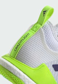 Weiße Sportschuhe mit strukturiertem Obermaterial, leuchtend grünen Akzenten, einem Zugtab mit der Aufschrift "CRAZYFLIGHT" und einer strukturierten Gummisohle.