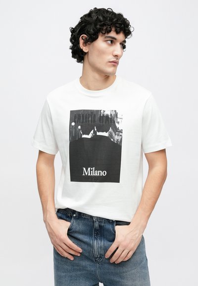 Biele bavlnené tričko s čiernym grafickým dizajnom, obsahujúce nápis „Emporio Armani“ a potlač „Milano“ v spodnej časti. Krátke rukávy, okrúhly výstrih.