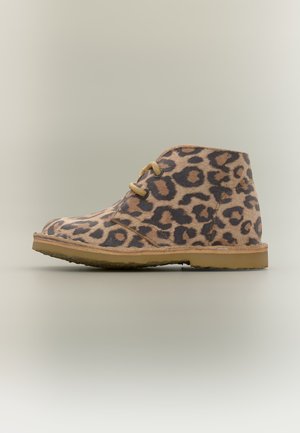 Botte de désert montant à la cheville avec un motif léopard beige et noir, des lacets couleur fauve et une semelle en caoutchouc marron clair sur fond uni.