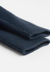 Manches de pull en tricot bleu marine avec texture côtelée ; mélange de laine doux et confortable ; soigneusement plié, mettant en valeur des bords nets et des coutures uniformes.