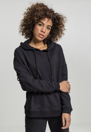 Black hoodie with a drawstring hood, featuring a relaxed fit, looped lacing detail on the sleeves, and ribbed cuffs and hem.
