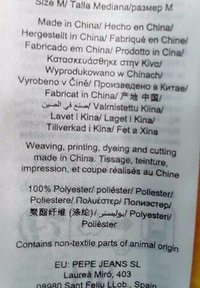 Oznaka s tekstom o njezi tkanina, materijalima i pojedinostima o proizvodnji. 100% poliester, proizvedeno u Kini, uključene upute na više jezika.