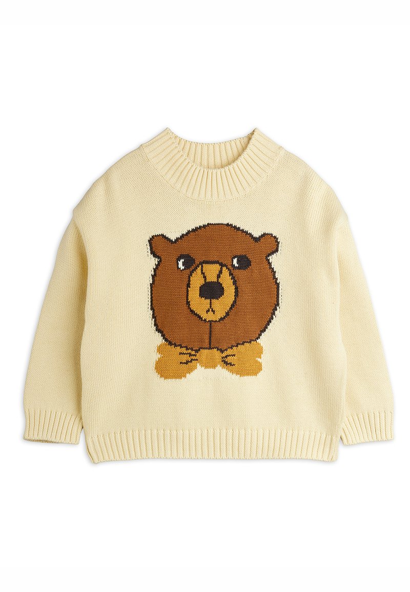 Suéter de punto color crema con un gráfico de un oso marrón que lleva corbata de moño. Cuello y puños acanalados. Tejido suave y texturizado.