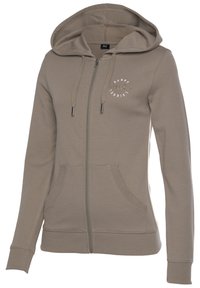 Helle braune Zip-Hoodie aus weichem Material. Verfügt über eine Kapuze, Kängurutaschen, gerippte Bündchen und ein kleines Grafiklogo auf der Brust.